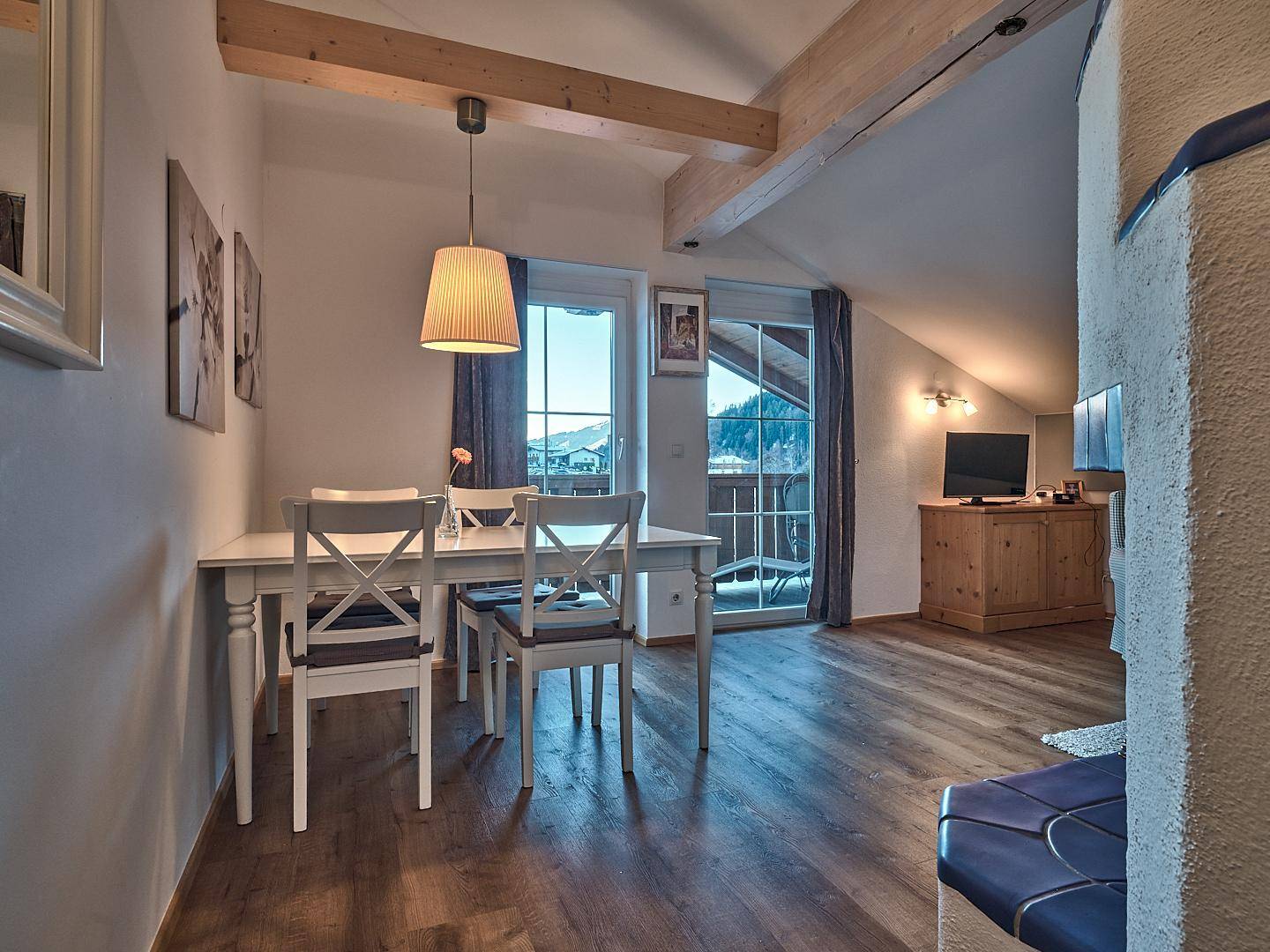 Heller Essbereich mit Holztisch und Stühlen, Balkonzugang und einem schönen Bergblick.