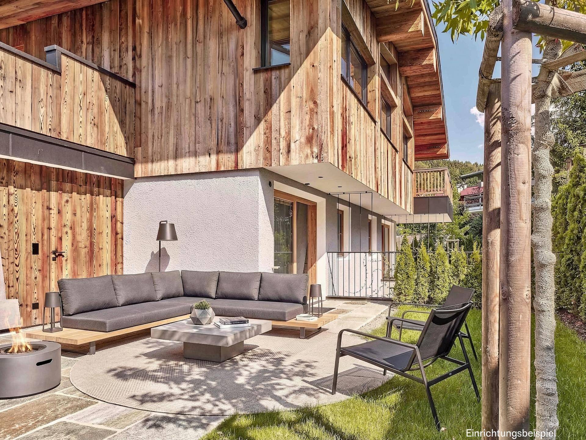 Ebenerdige Terrasse mit moderner Lounge-Sitzgruppe, Feuerstelle und direktem Zugang zum gepflegten Rasenbereich.