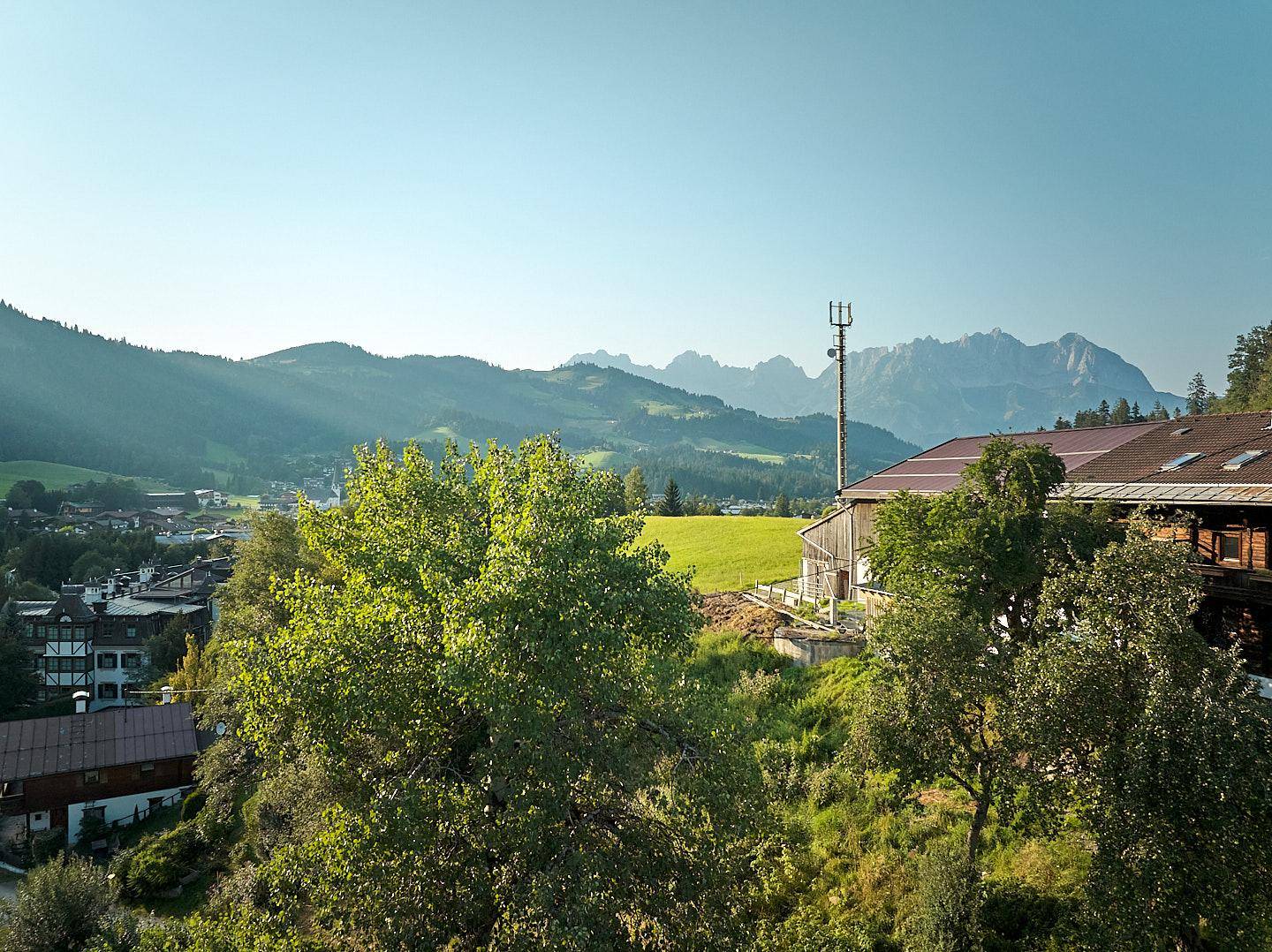Malerischer Ausblick auf grüne Hügel und majestätische Berge unter einem klaren blauen Himmel.