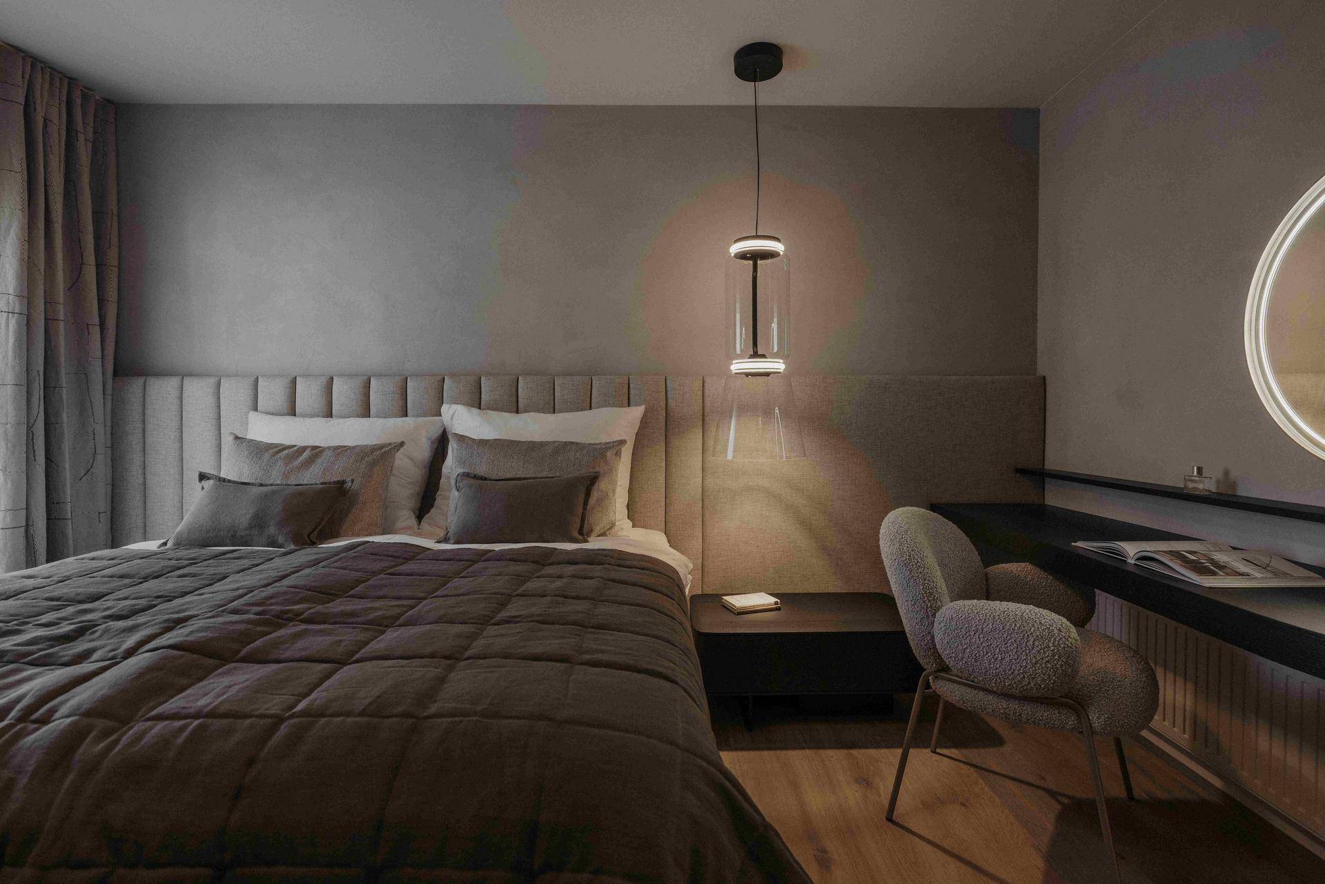 Modernes Schlafzimmer mit gepolstertem Kopfteil, Holzboden und stilvoller Beleuchtung.