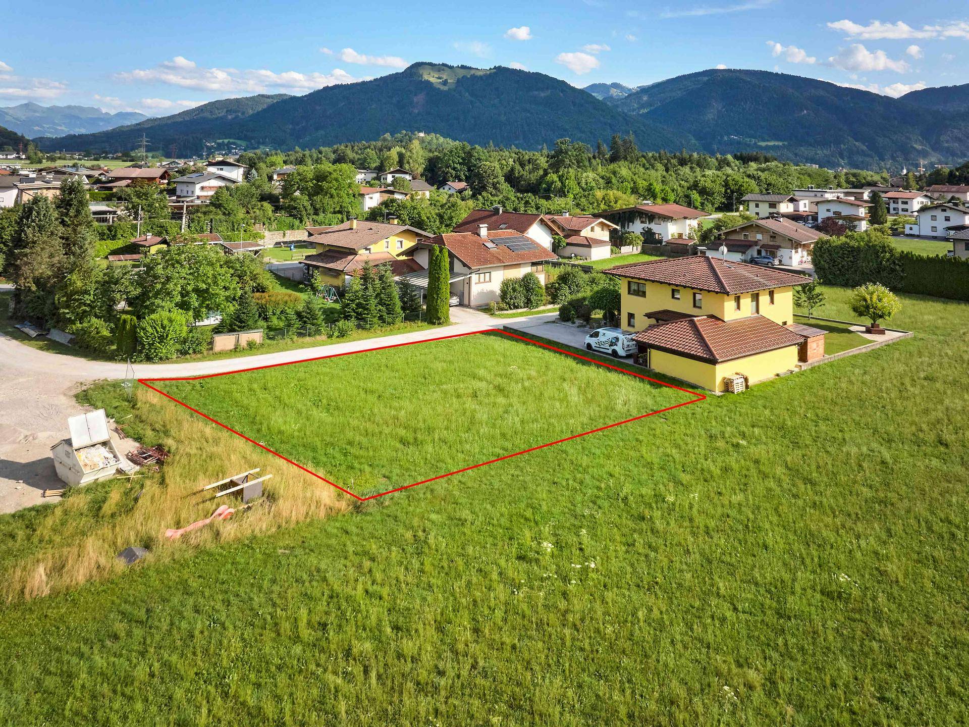 Luftaufnahme eines freien Baugrundstücks in einer ruhigen Wohnsiedlung mit Bergblick.