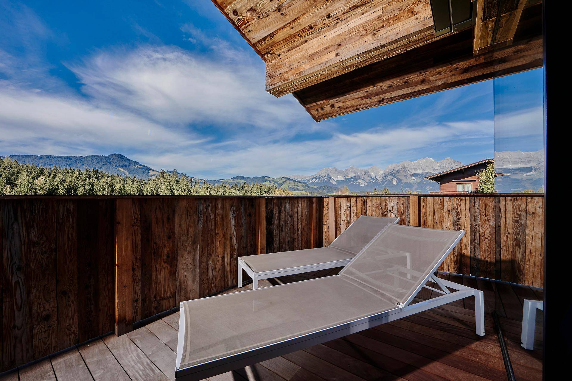 Sonniger Balkon mit Liegestühlen und atemberaubendem Blick auf die Alpenlandschaft.