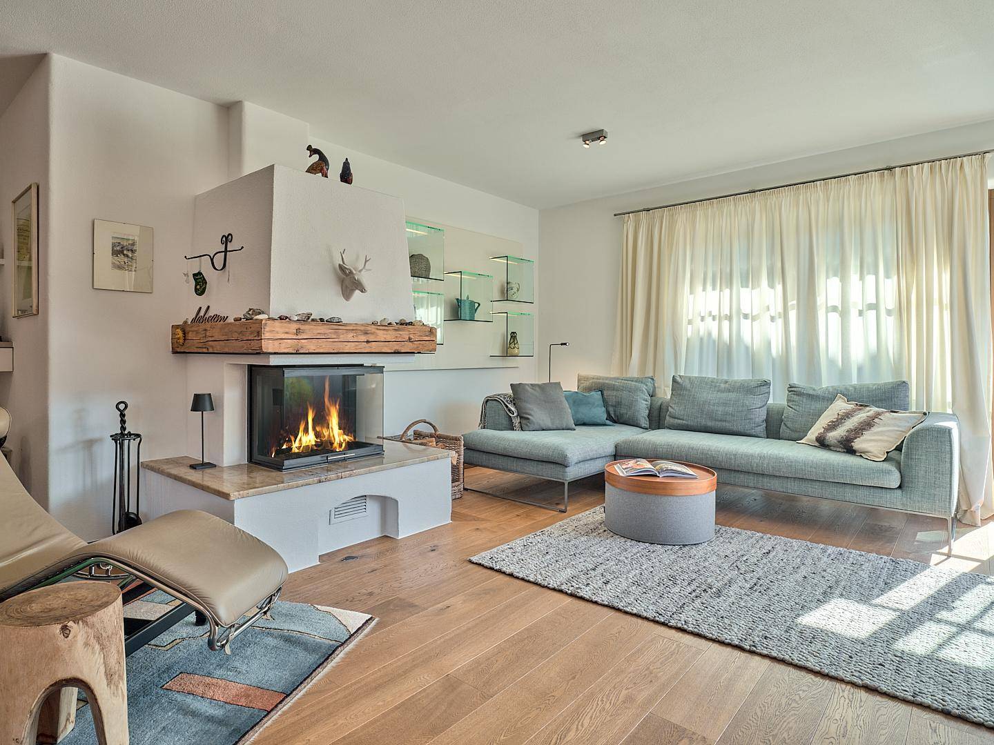 Helles Wohnzimmer mit modernem Kamin, bequemer Couch und Holzboden.
