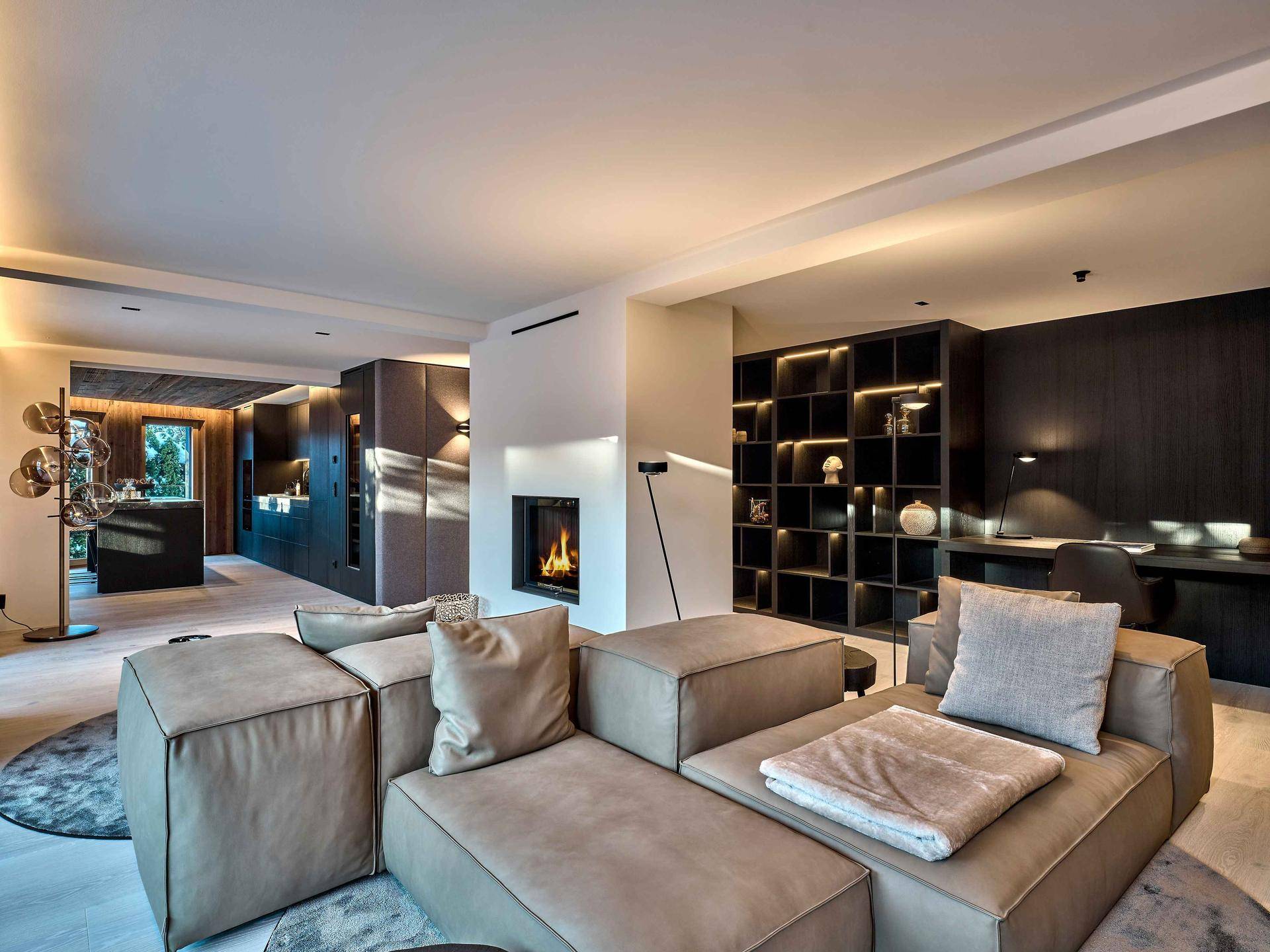 Geräumiges Wohnzimmer mit modernem Kamin, bequemen Sofas und integriertem Arbeitsbereich.