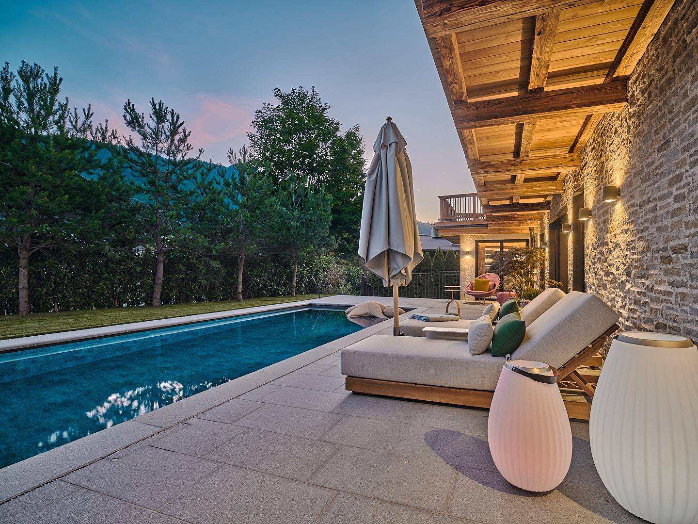 Elegante Poolterrasse mit bequemen Sonnenliegen und Blick auf die umliegende Berglandschaft.