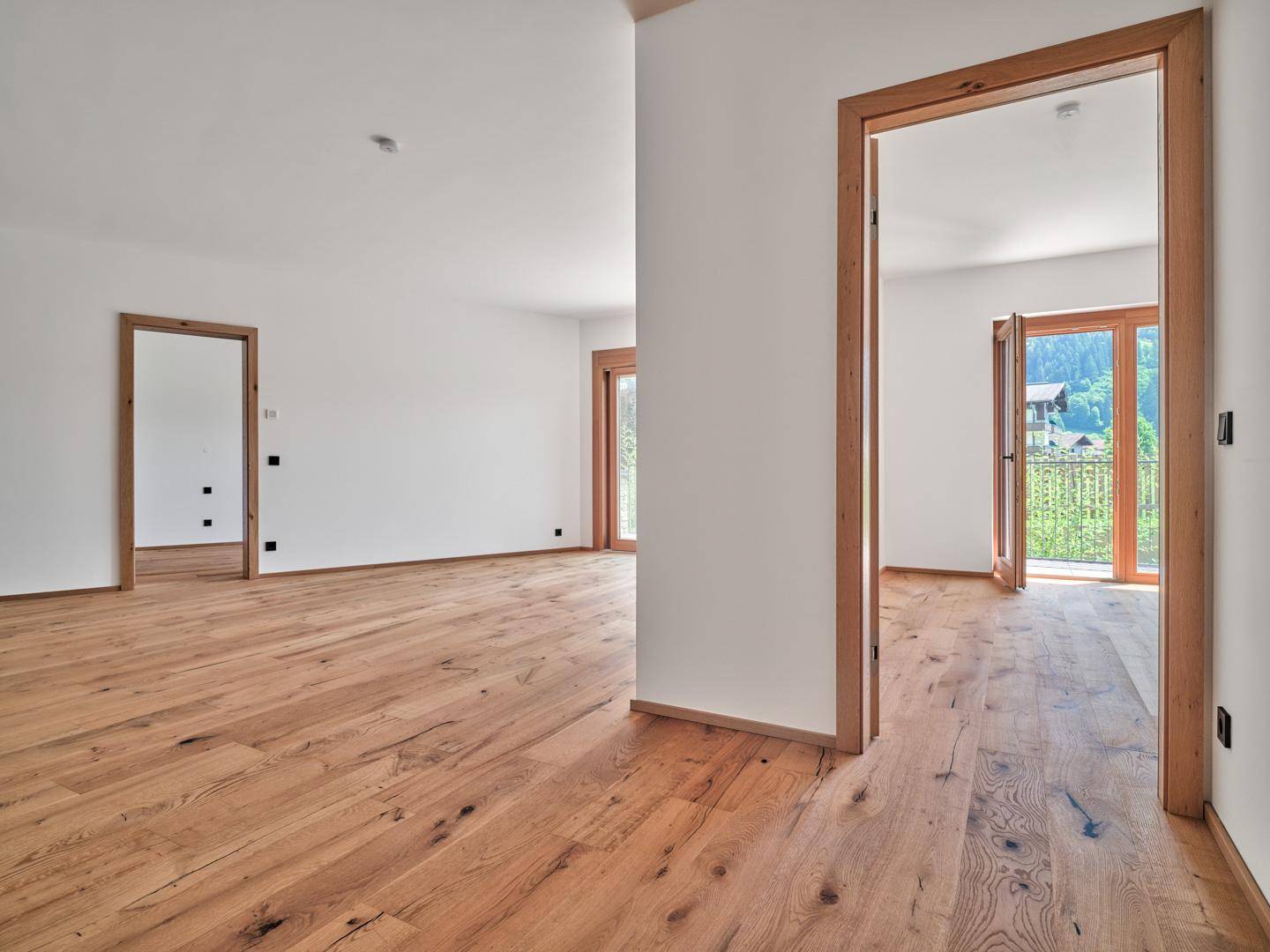 Geräumiger, unmöblierter Innenraum mit hellem Holzboden und mehreren Türen, bereit zur individuellen Gestaltung.