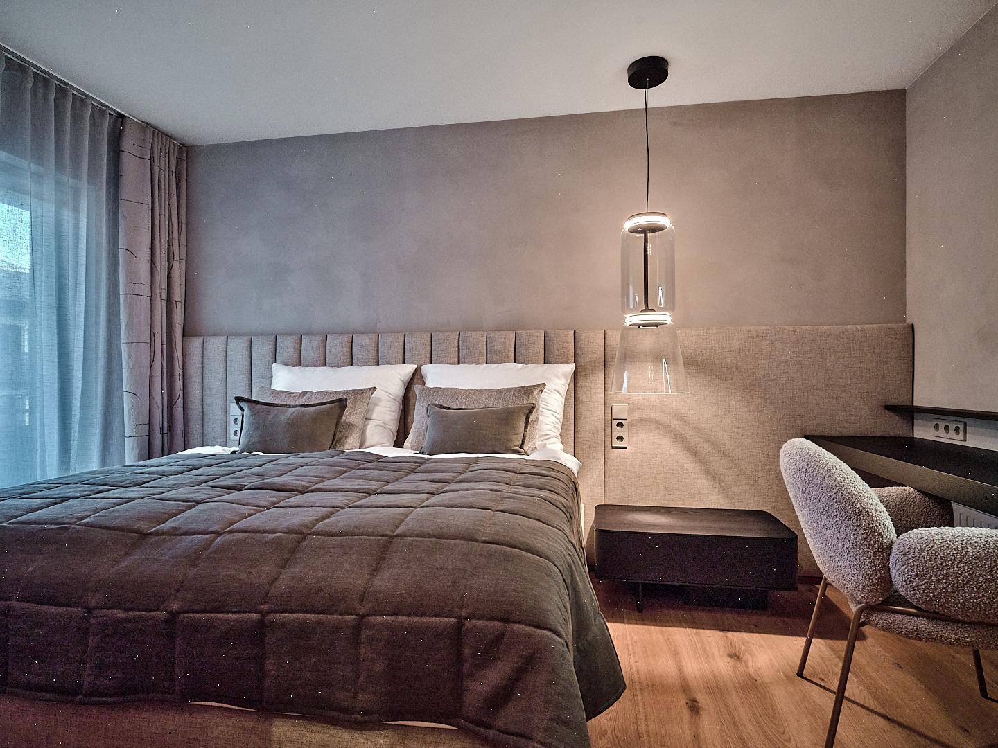 Modernes Schlafzimmer mit großem Bett, gepolstertem Kopfteil und stilvoller Beleuchtung.