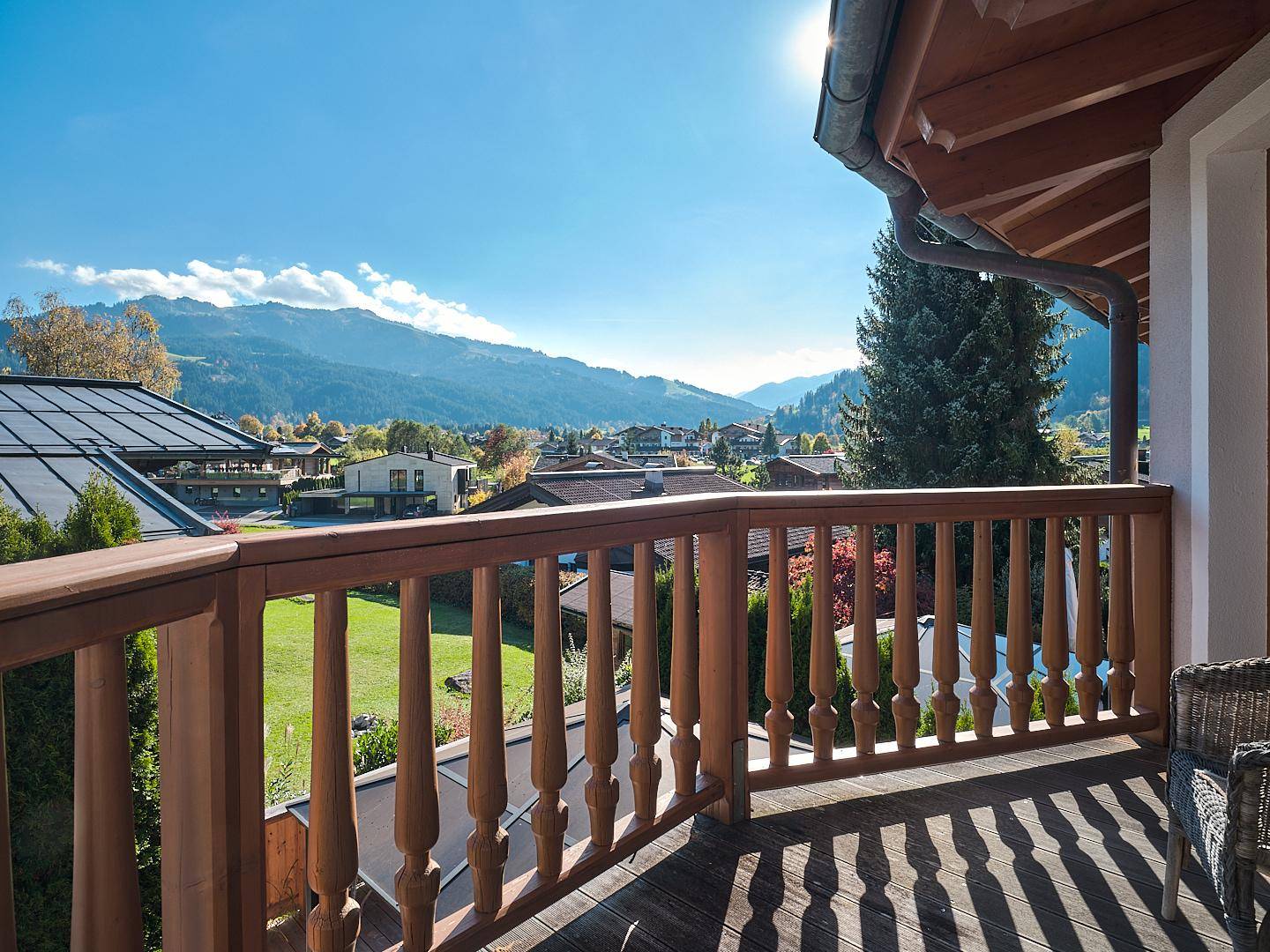 Sonniger Balkon mit Holzgeländer und weitem Blick auf die Berge und die umliegende Landschaft.