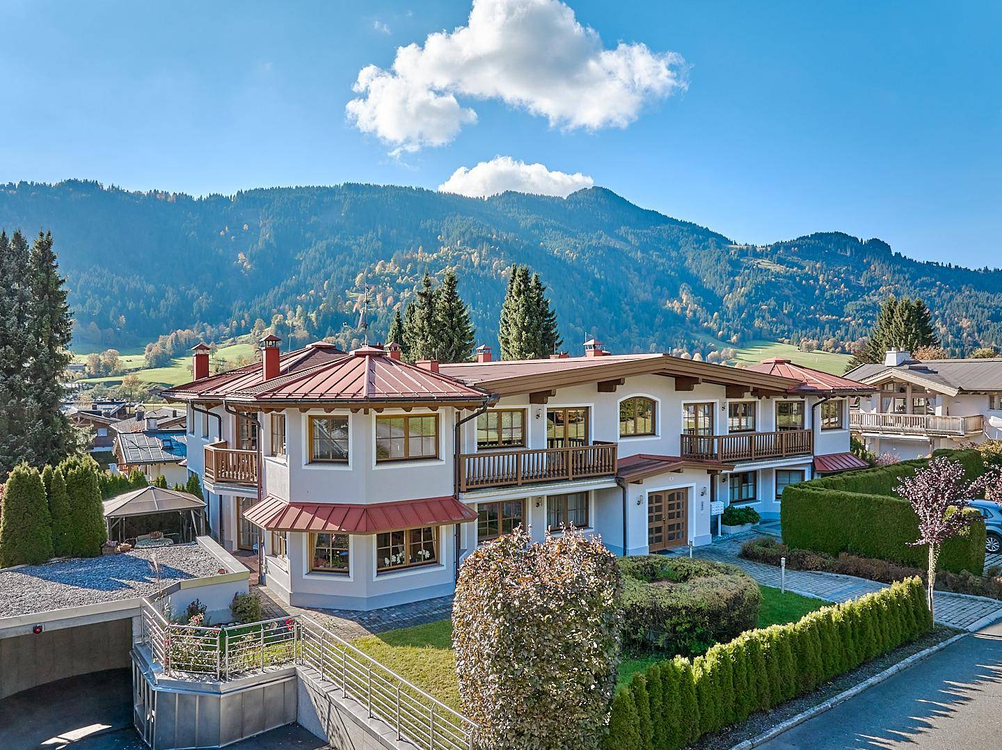 Attraktives Wohnhaus mit mehreren Balkonen, umgeben von grüner Landschaft und Bergen.
