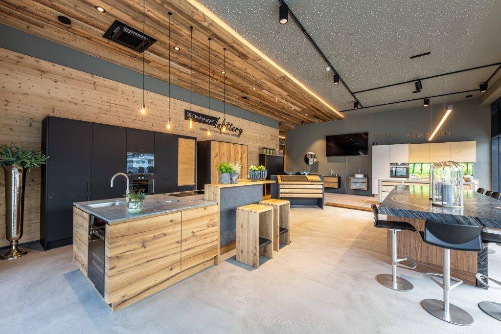 Moderner Küchenausstellungsraum mit Holzelementen, dunklen Schränken und verschiedenen Kücheninseln.