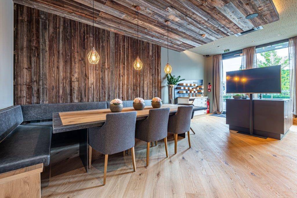 Rustikaler Essbereich mit Holzwänden und -decke, großem Esstisch und modernem Fernseher.