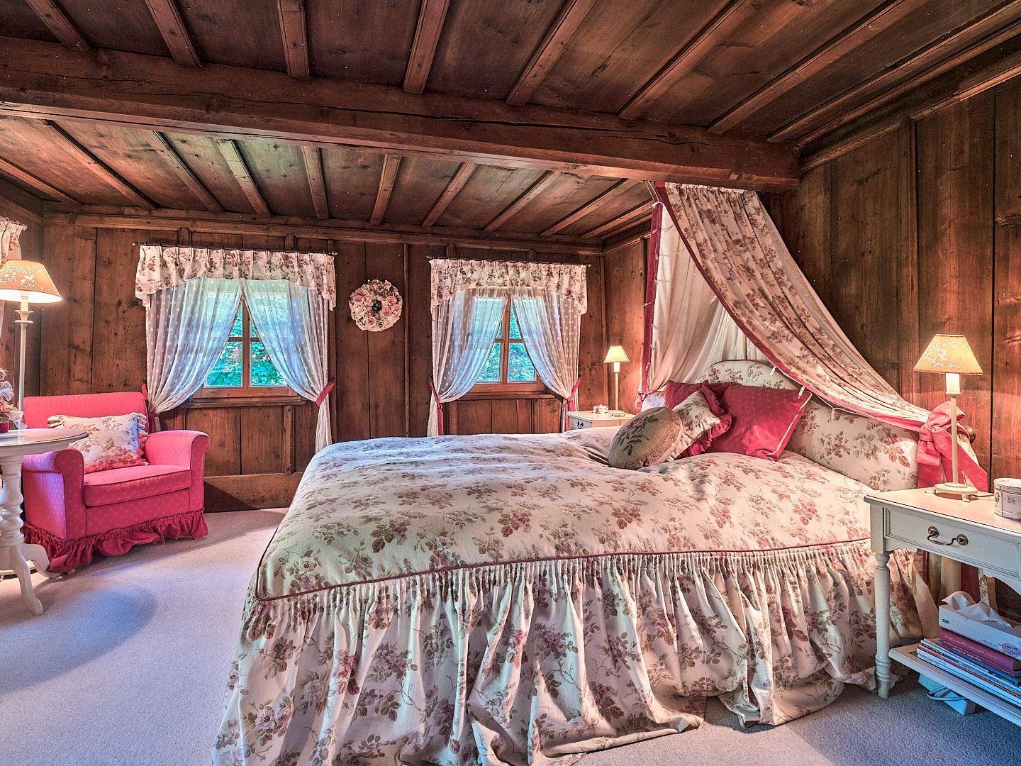 Gemütliches Schlafzimmer mit Holztäfelung, Himmelbett und floralen Mustern in traditionellem Stil.