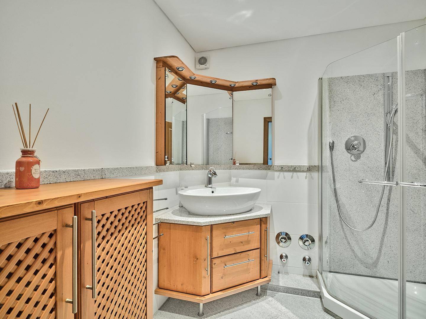 Modernes Badezimmer mit Duschkabine, Einzelwaschbecken und Holzmöbeln.