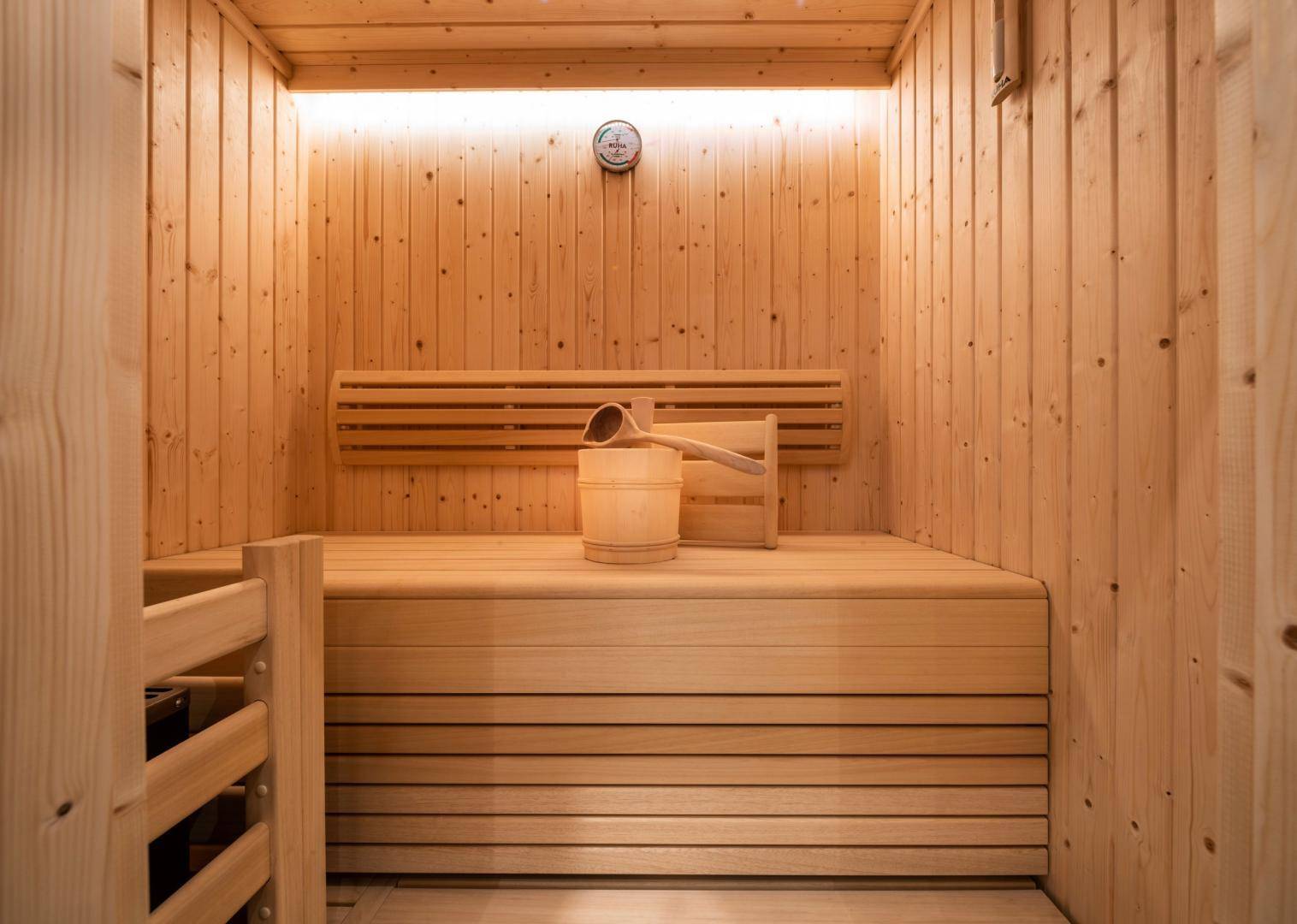 Gemütliche Holzsauna mit traditionellem Aufgusseimer und Sanduhr.
