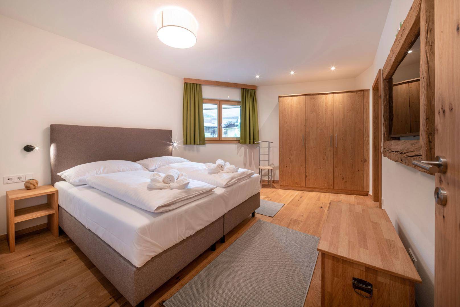 Helles Schlafzimmer mit Doppelbett, Holzboden und großem Kleiderschrank.