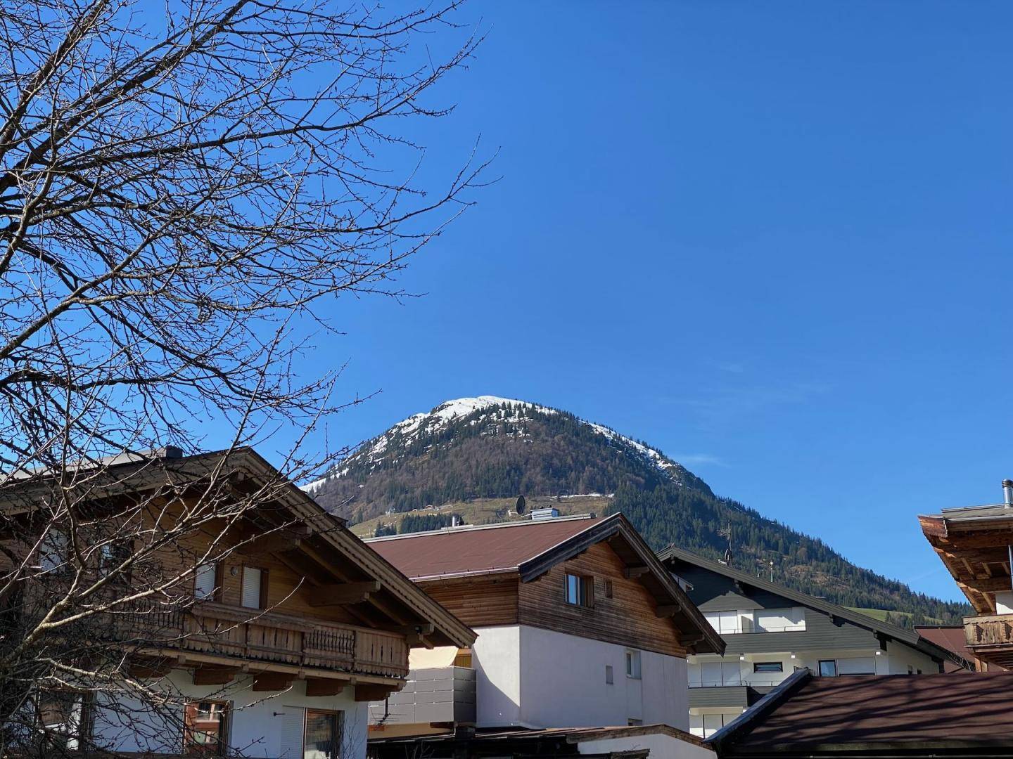Malerischer Blick auf schneebedeckte Berge und traditionelle Häuser in der Ferne.