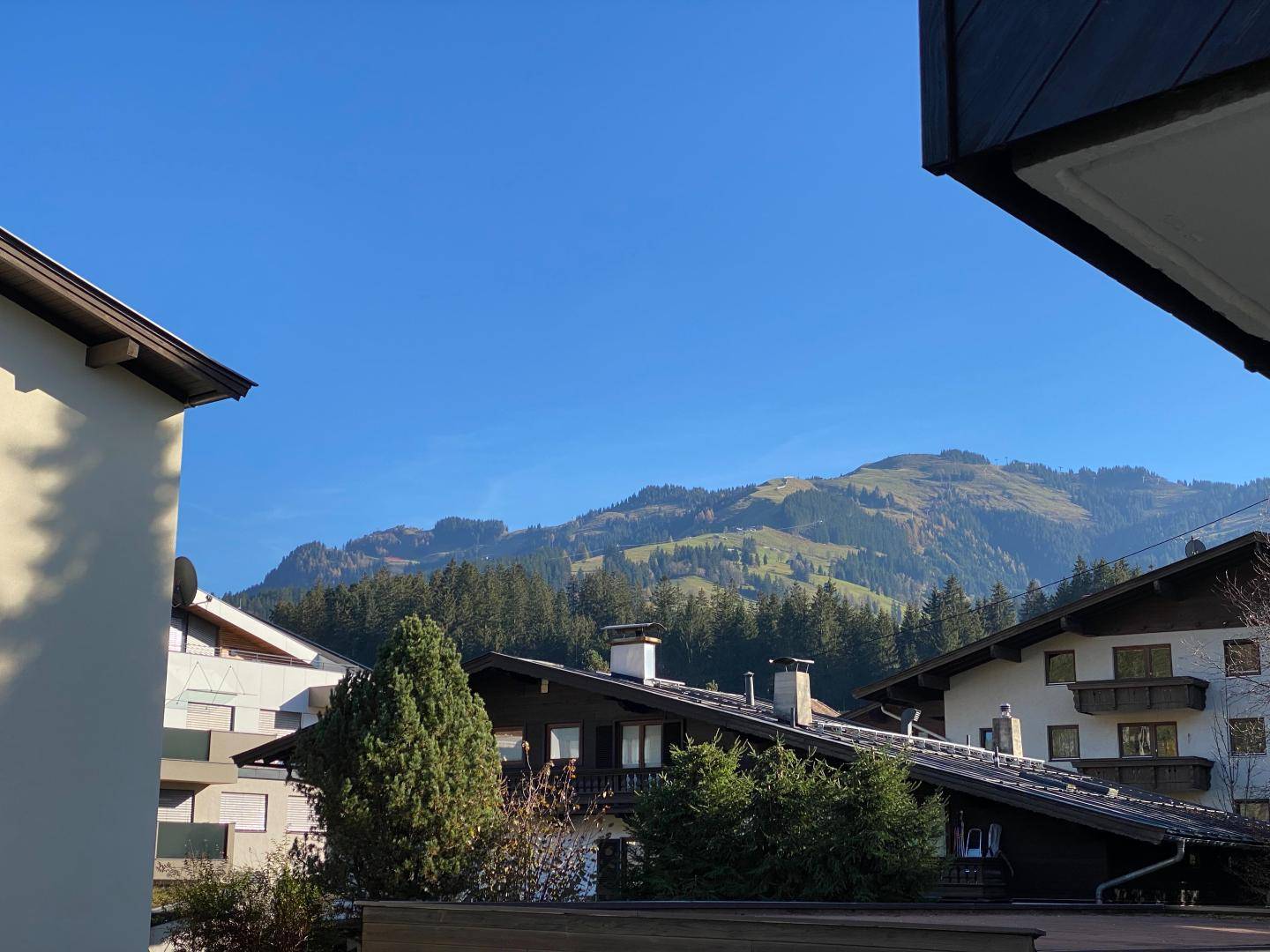 Weitläufiger Blick auf grüne Hügel und bewaldete Berge unter blauem Himmel.
