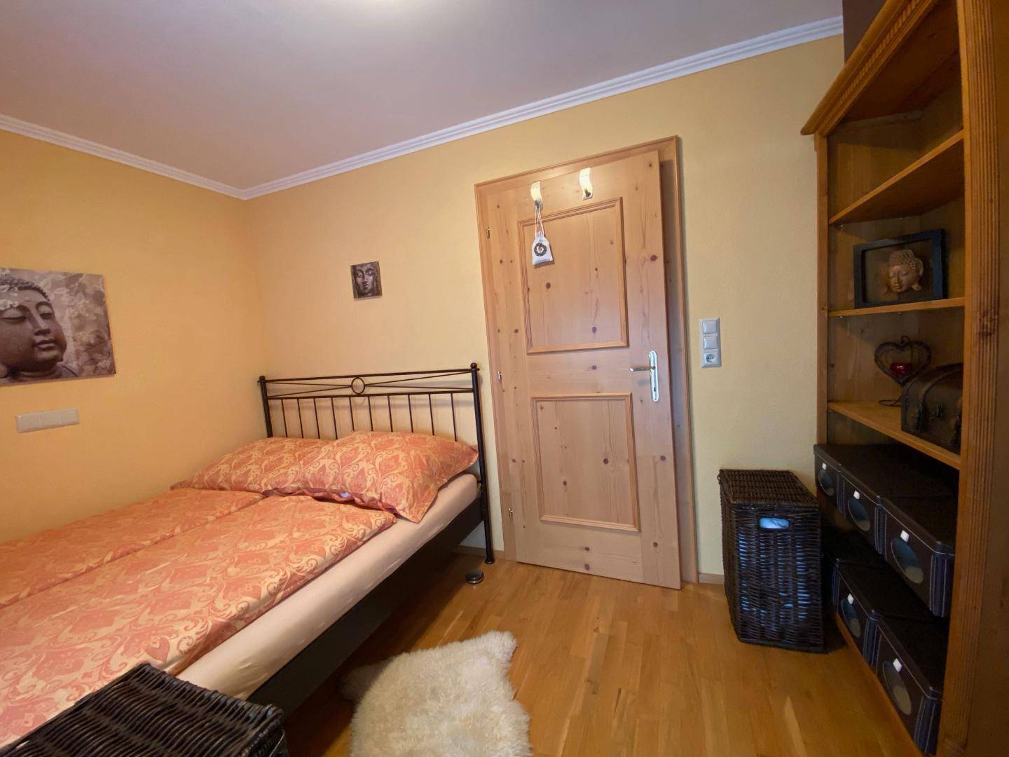 Gemütliches Schlafzimmer mit Einzelbett, Holzboden und Regal.