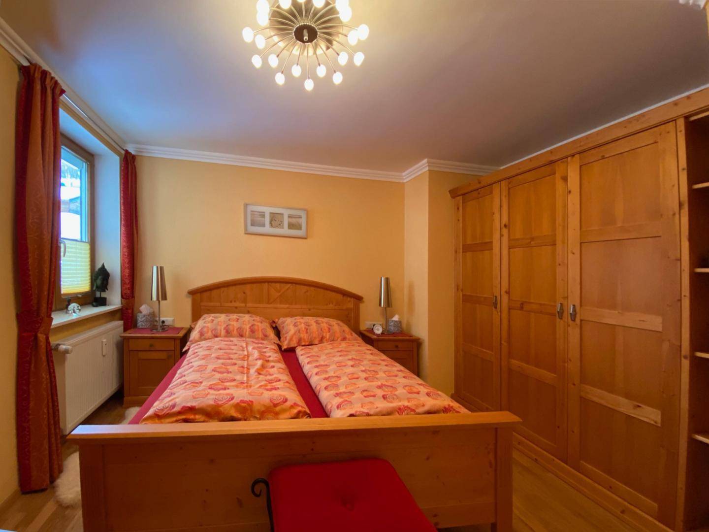 Schlafzimmer mit Doppelbett, Holzmöbeln und einem großen Kleiderschrank.