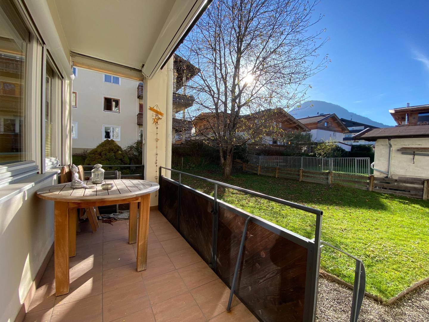Sonniger Terrassenbereich mit kleinem Tisch und Blick auf den Garten und die Berge.