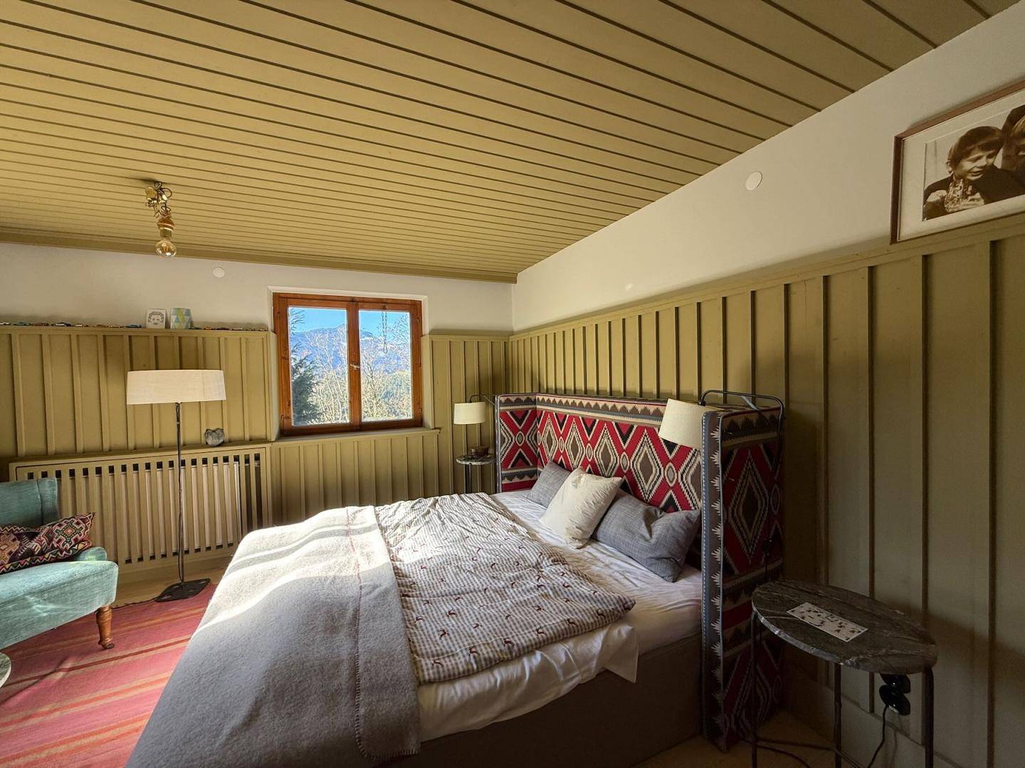 Geräumiges Schlafzimmer mit traditionellem Kopfteil, Holzelementen und viel Tageslicht.