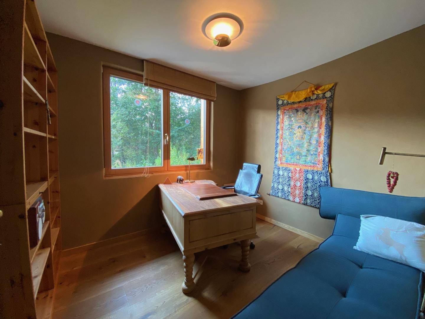 Ruhiges Arbeitszimmer mit Holzboden, großem Fenster und Blick ins Grüne.