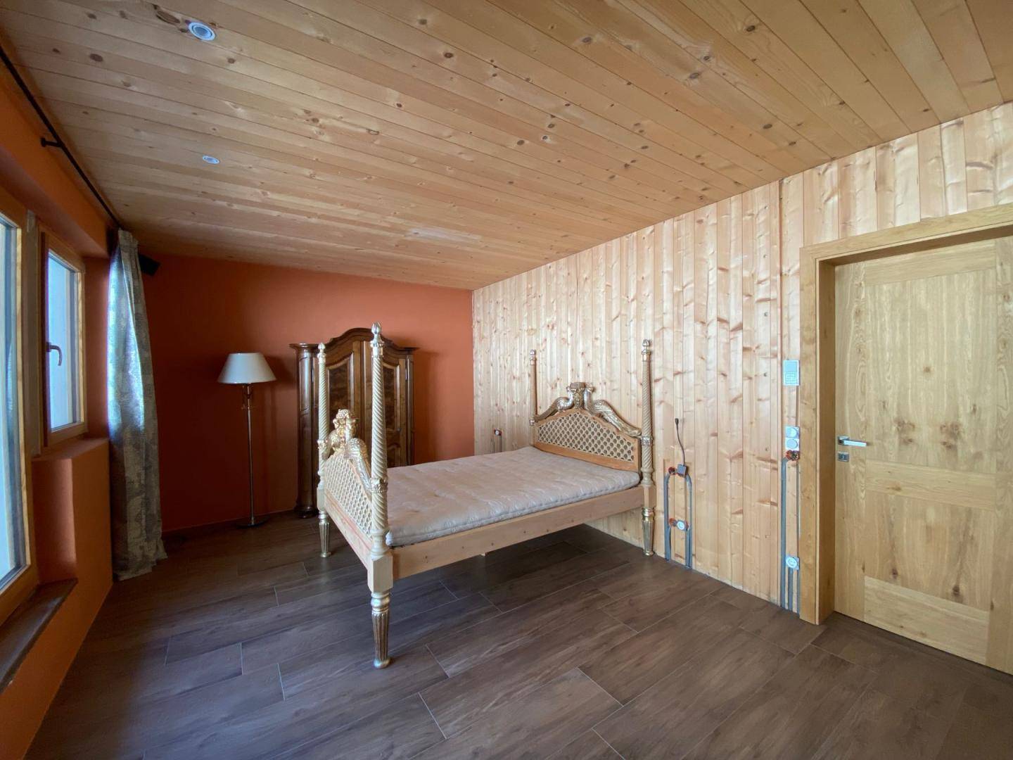 Geräumiges Schlafzimmer mit Holzboden, Holzdecke und orangefarbenen Wänden.