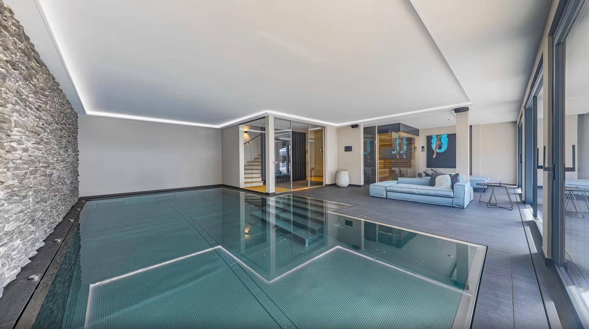 Exklusiver Wellnessbereich mit Innenpool, Sauna und Steinwand für Entspannung.