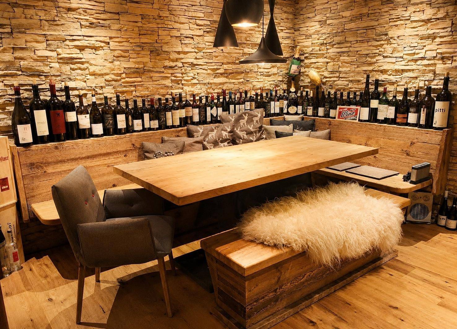 Rustikaler Weinkeller mit langer Holztafel, Steinwand und gemütlichen Sitzbänken für gesellige Abende.