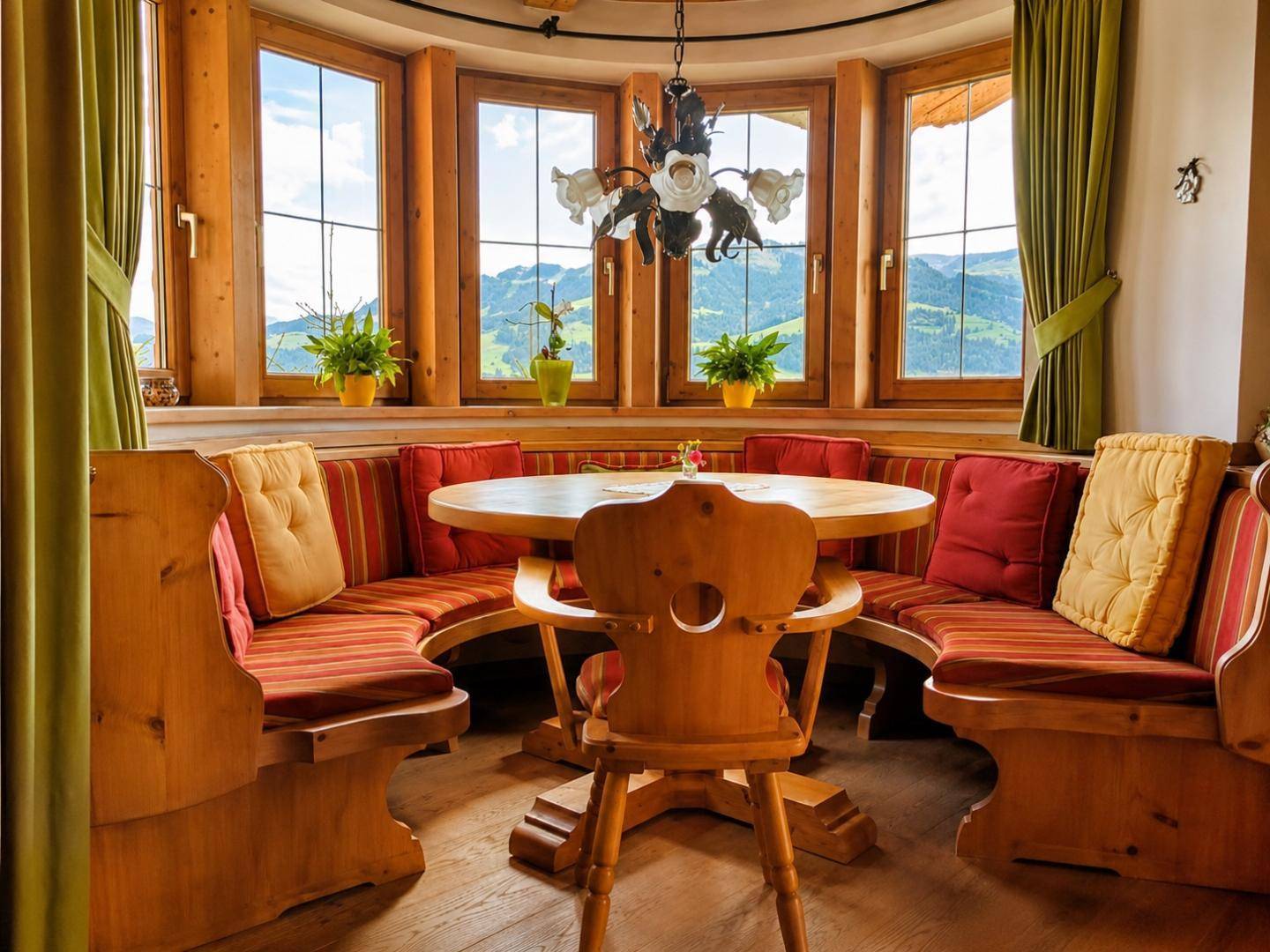 Traditioneller Essbereich mit Eckbank, Holztisch und Panoramafenstern mit Bergblick.