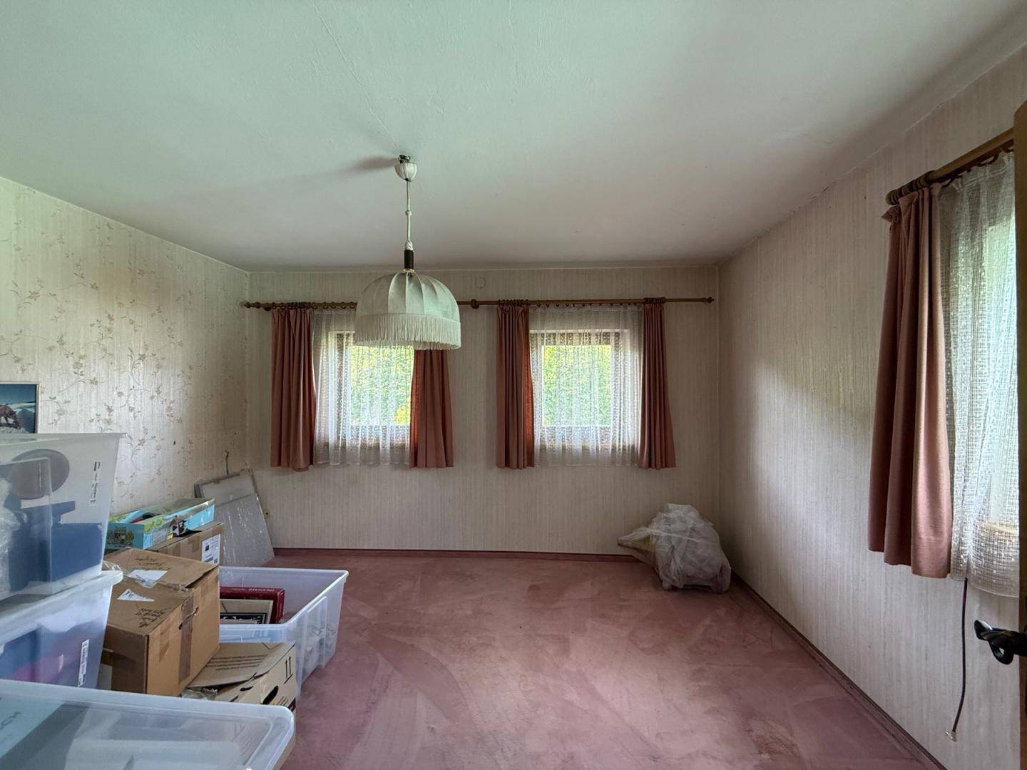 Geräumiges Schlafzimmer mit gemusterter Tapete, rosa Teppichboden und zwei Fenstern für natürliches Licht.