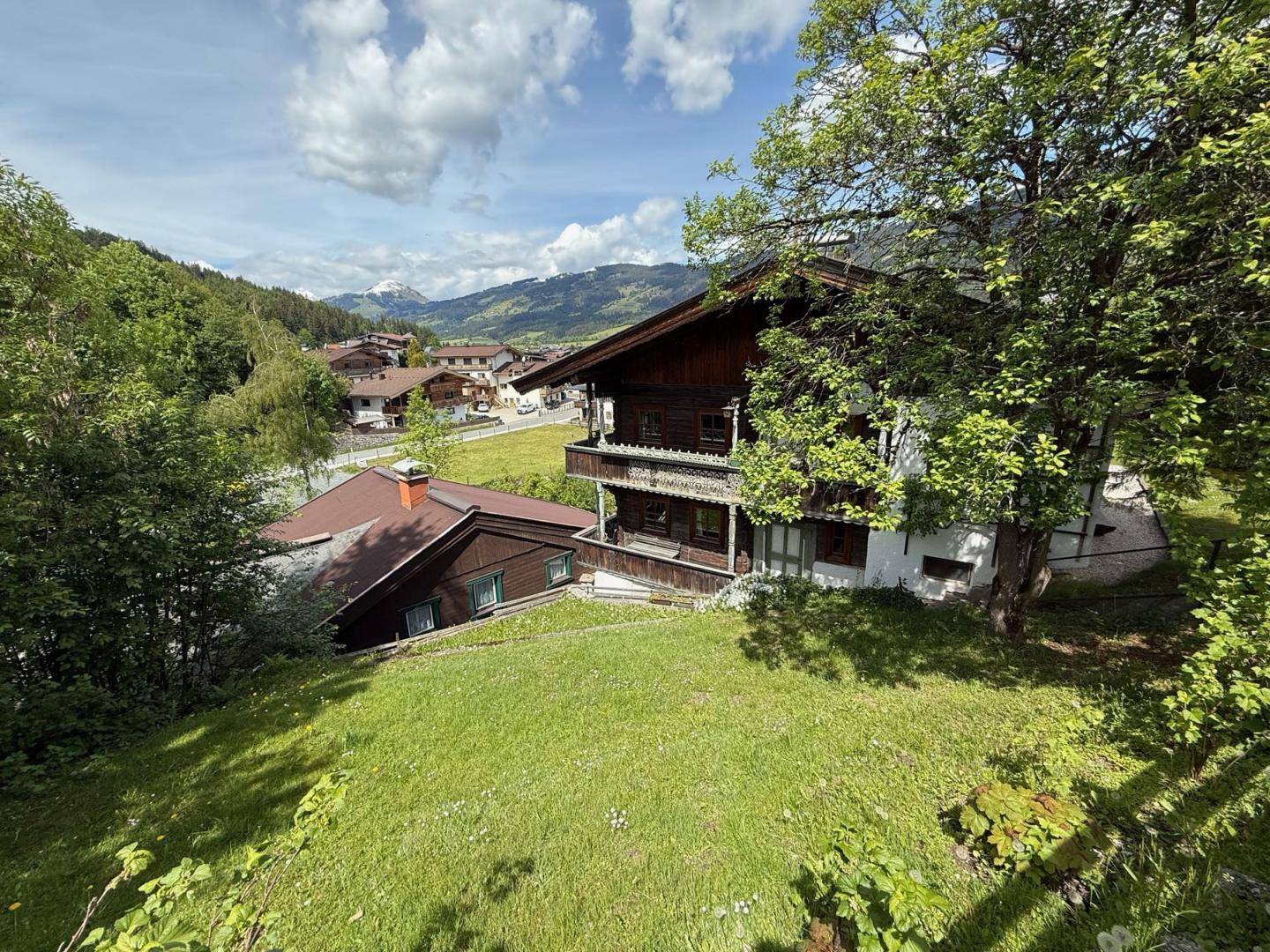 Malerisches Holzhaus in alpiner Umgebung mit Blick auf die umliegenden Berge und weitere Gebäude.