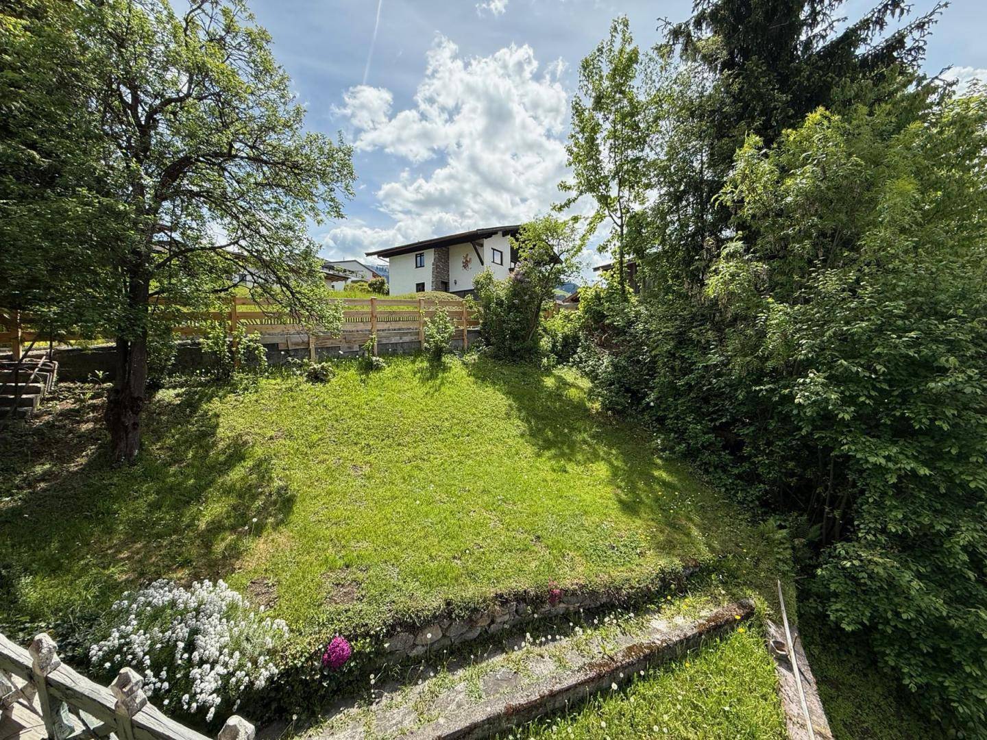 Gepflegter Gartenbereich mit Rasenfläche und Bäumen, der eine ruhige und grüne Umgebung bietet.
