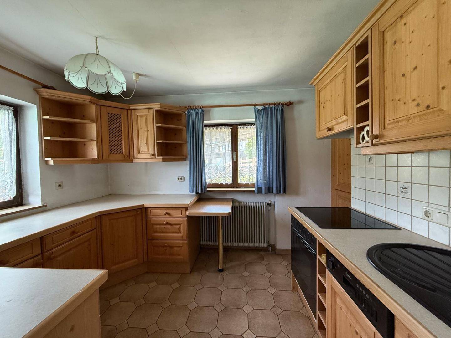Rustikale Küche mit Holzschränken, Fliesenboden und integrierten Kochfeldern, hell und funktional.