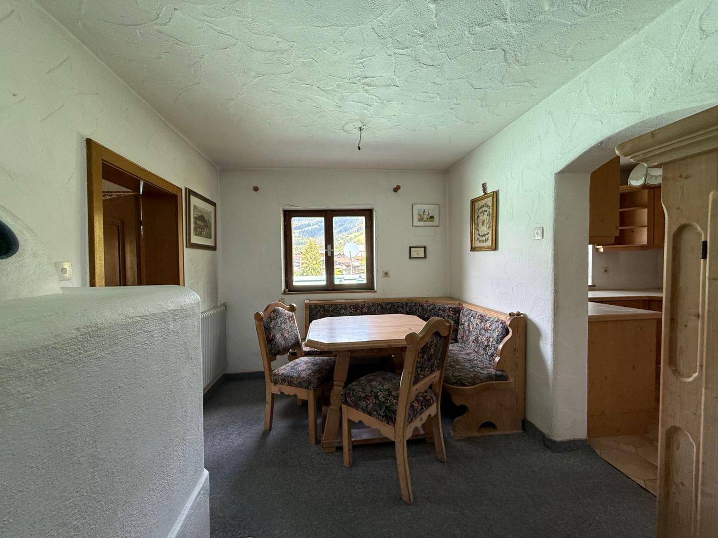 Traditioneller Essbereich mit Eckbank und Holztisch, angrenzend an eine Küche, mit Blick nach draußen.