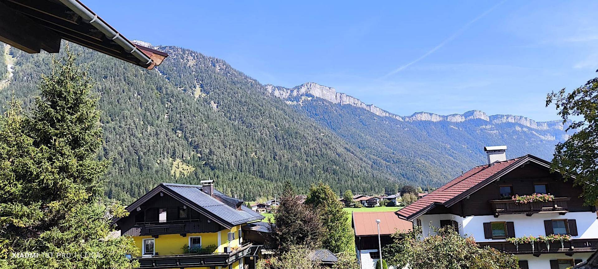 Malerische Bergkulisse mit traditionellen Häusern und üppiger Vegetation unter blauem Himmel.
