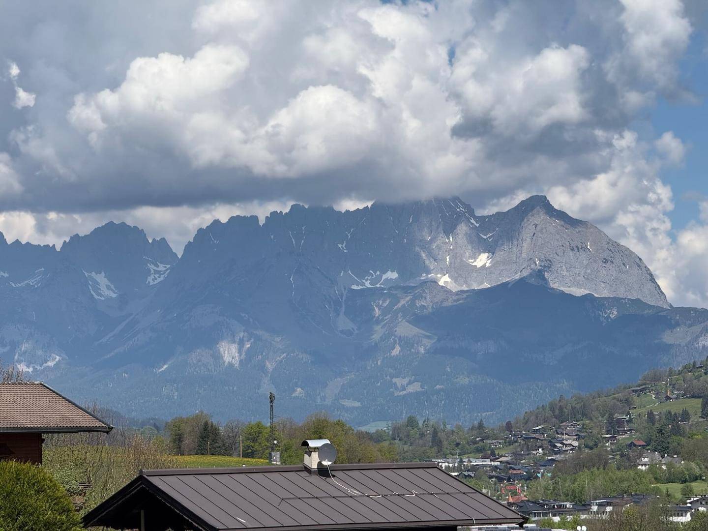 Panoramablick auf die majestätischen Berge mit bewölktem Himmel und grüner Landschaft im Vordergrund.