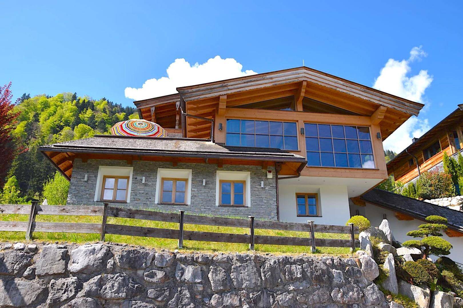 Charmantes Haus mit Holzfassade und Steinelementen, umgeben von einer malerischen Bergkulisse.