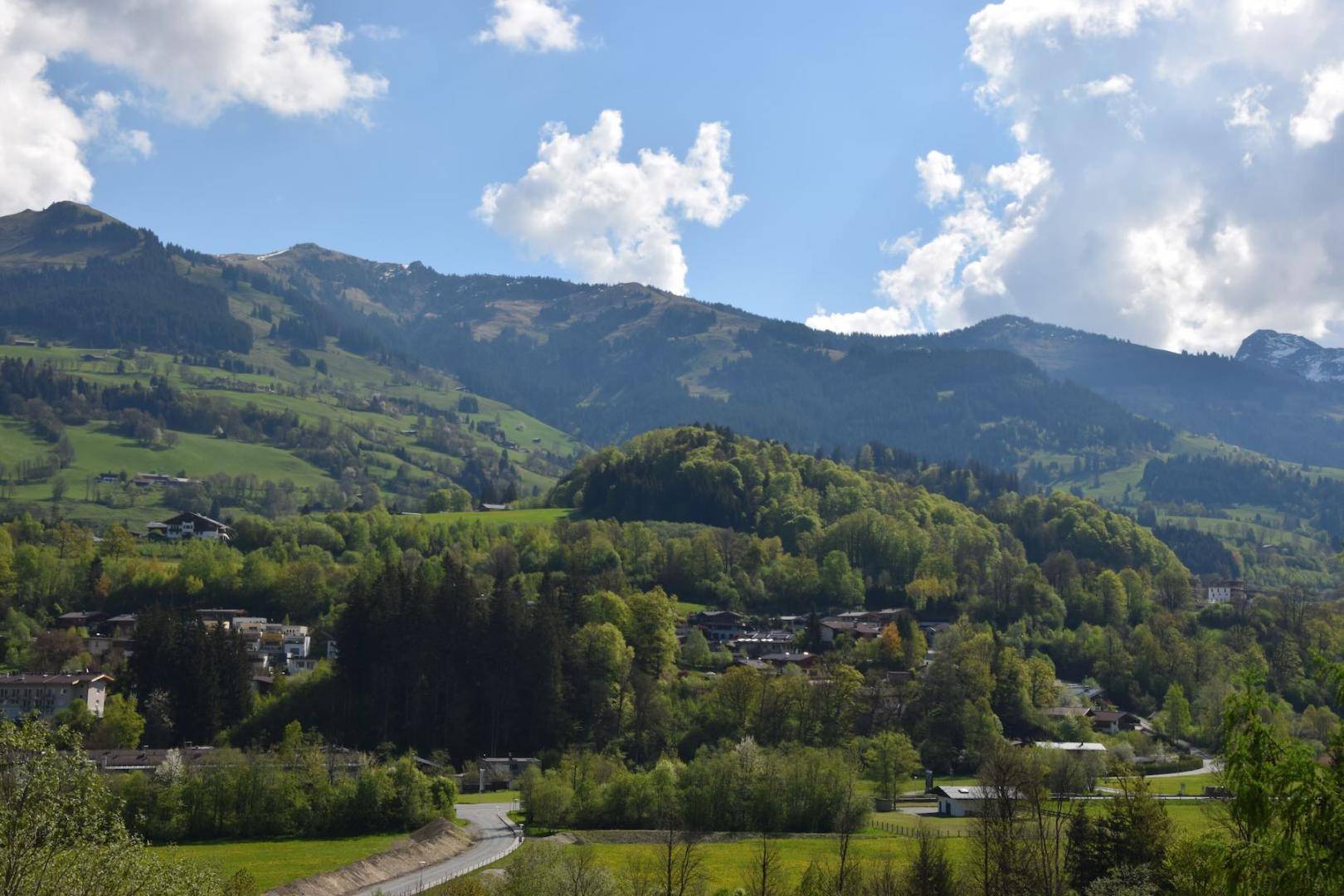 Idyllische Landschaft mit sanften Hügeln, grünen Wäldern und kleinen Siedlungen im Tal.