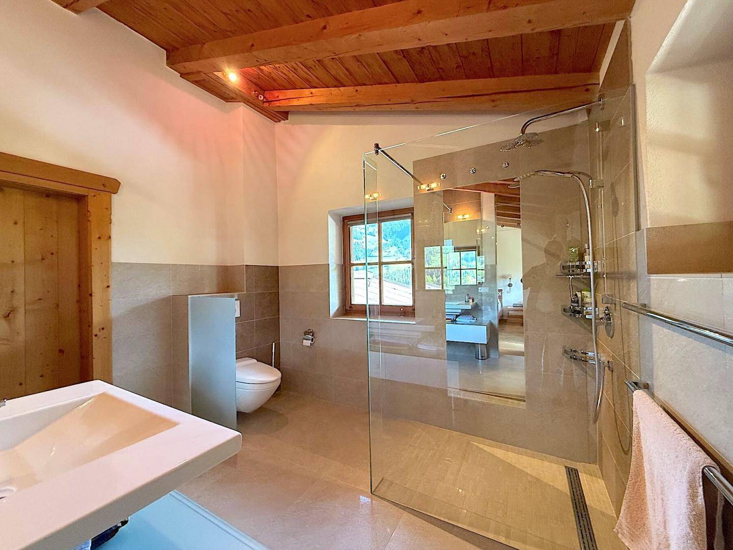 Modernes Badezimmer mit begehbarer Dusche, Wand-WC und Fenster mit Bergblick.