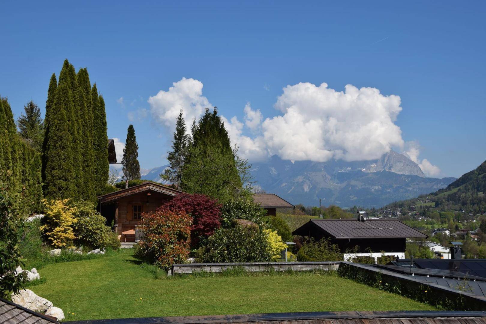 Gepflegter Garten mit Rasenfläche und Blick auf die umliegende Berglandschaft.