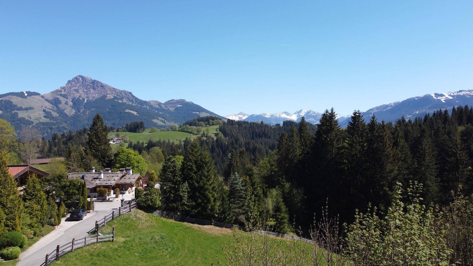 Malerische Berglandschaft mit bewaldeten Hügeln und traditionellen Häusern in der Ferne.