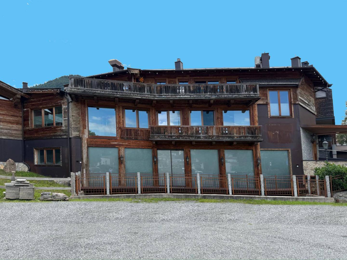 Rustikales Gebäude mit Holzfassade, großen Fenstern und einem Balkon im oberen Stockwerk, gut gepflegt.