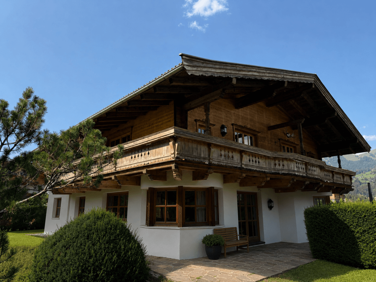 Traditionelles Holzhaus im alpinen Stil mit Balkonen und gepflegtem Gartenbereich.