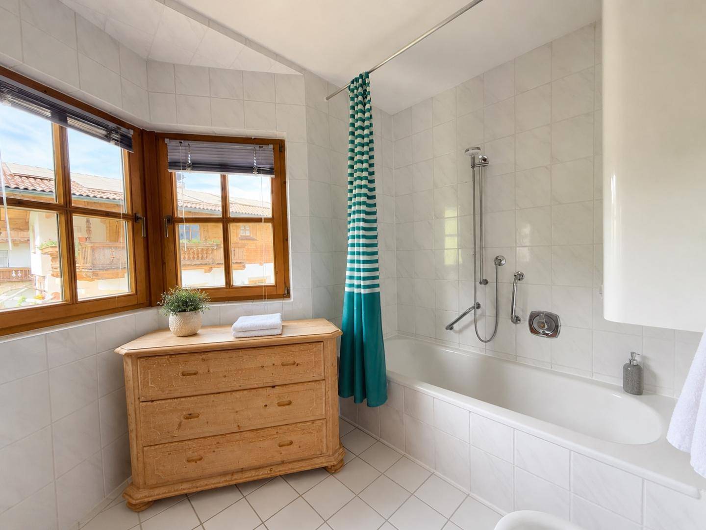 Helles Badezimmer mit Badewanne, weißen Fliesen und Fenster.