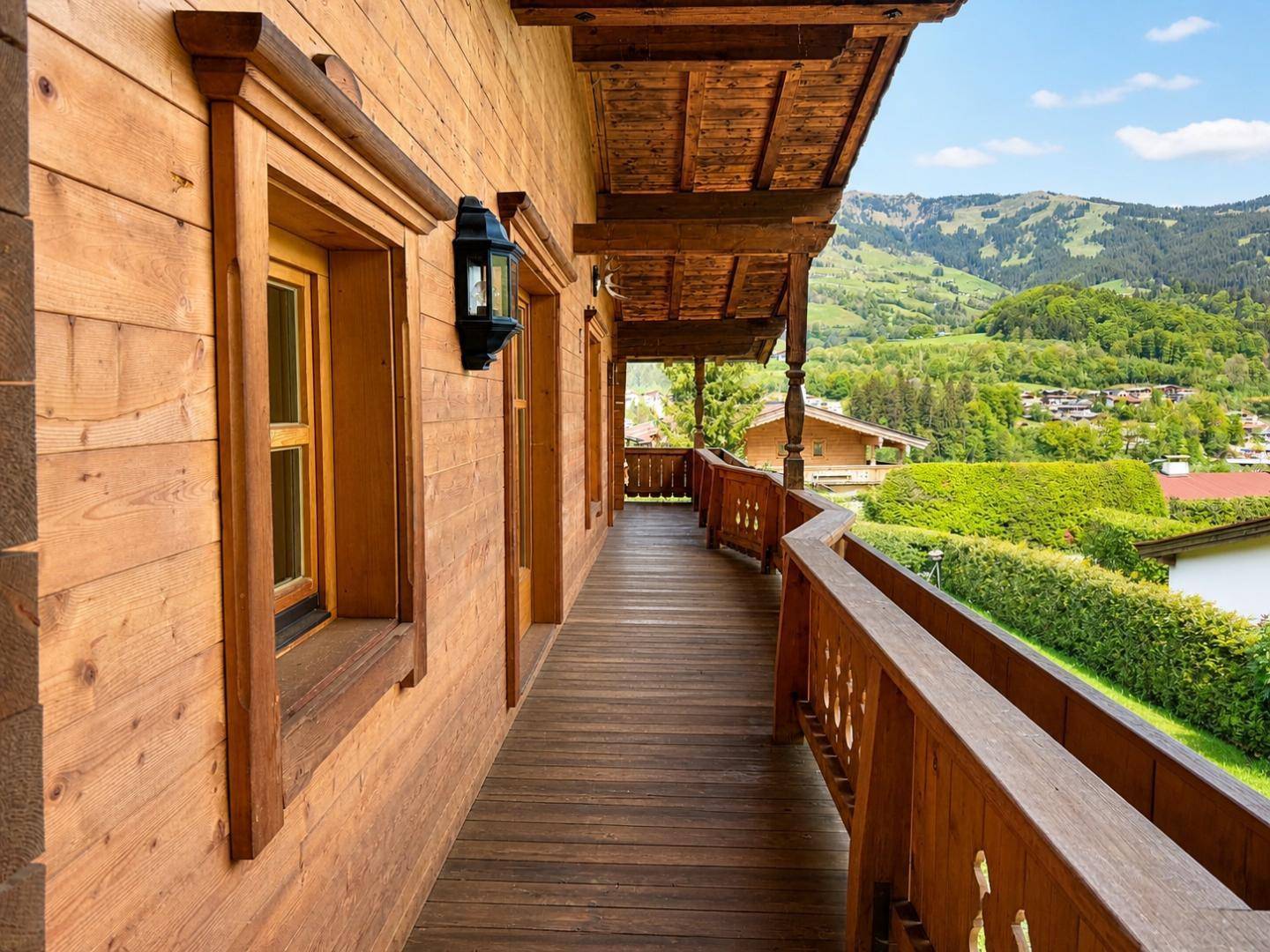 Langer Holzbalkon mit traditionellem Geländer und Bergblick.