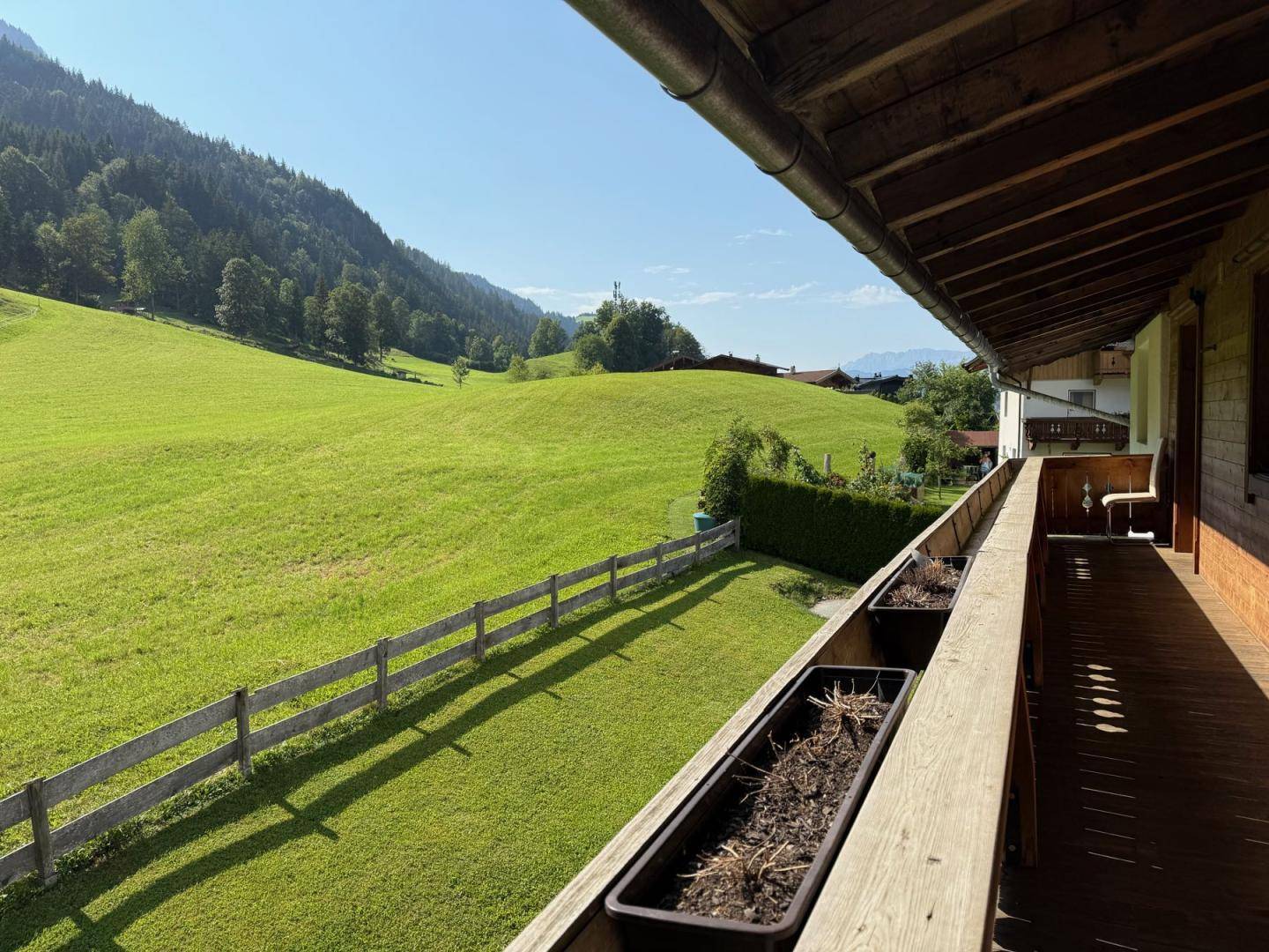 Sonniger Balkon mit weitem Blick über grüne Wiesen und Berge.