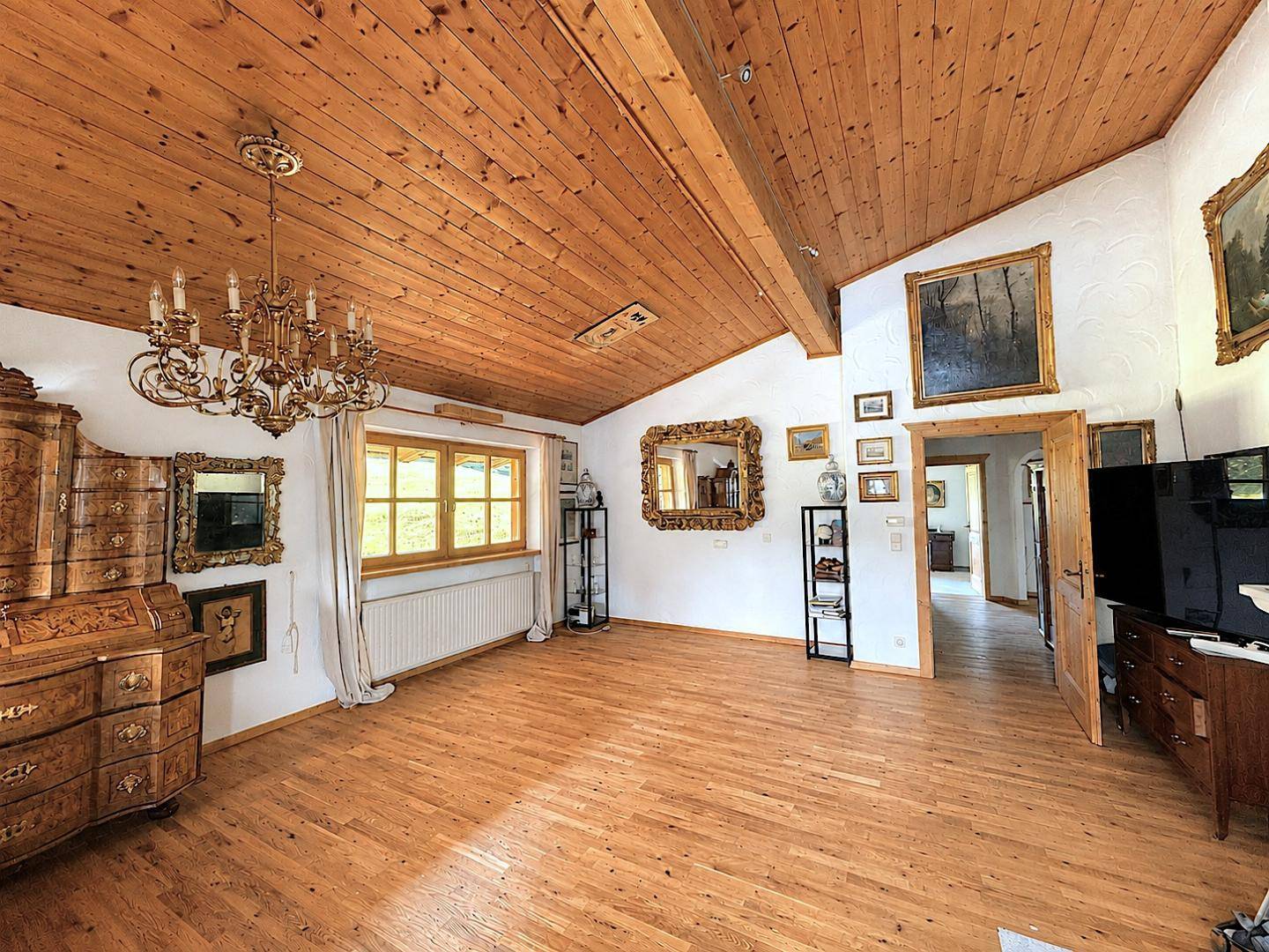 Geräumiges Wohnzimmer mit Holzbalkendecke, Parkettboden und traditionellen Möbeln.