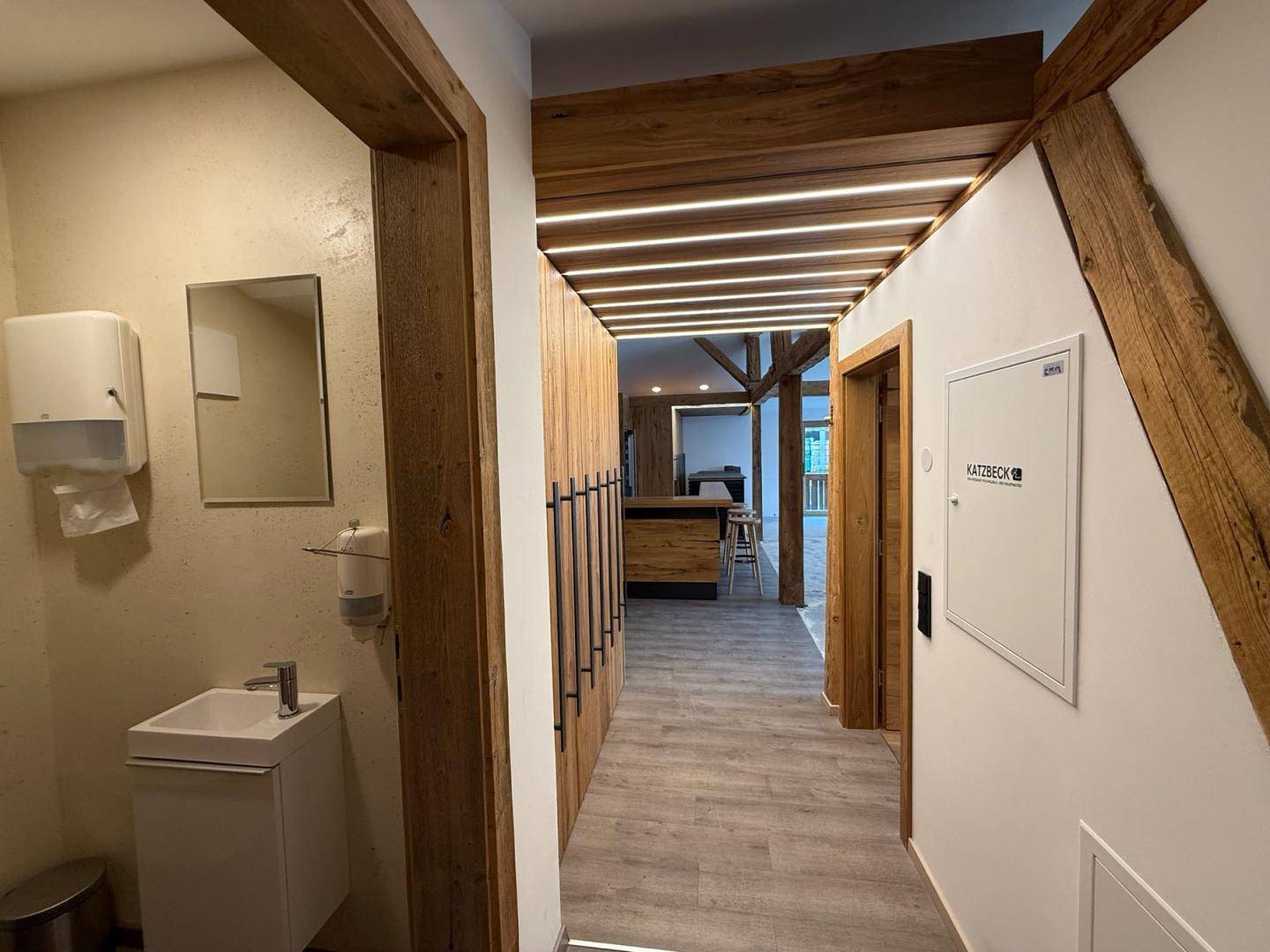 Moderner Flur mit Holzverkleidung, integrierter Beleuchtung und Zugang zu den Sanitärbereichen.