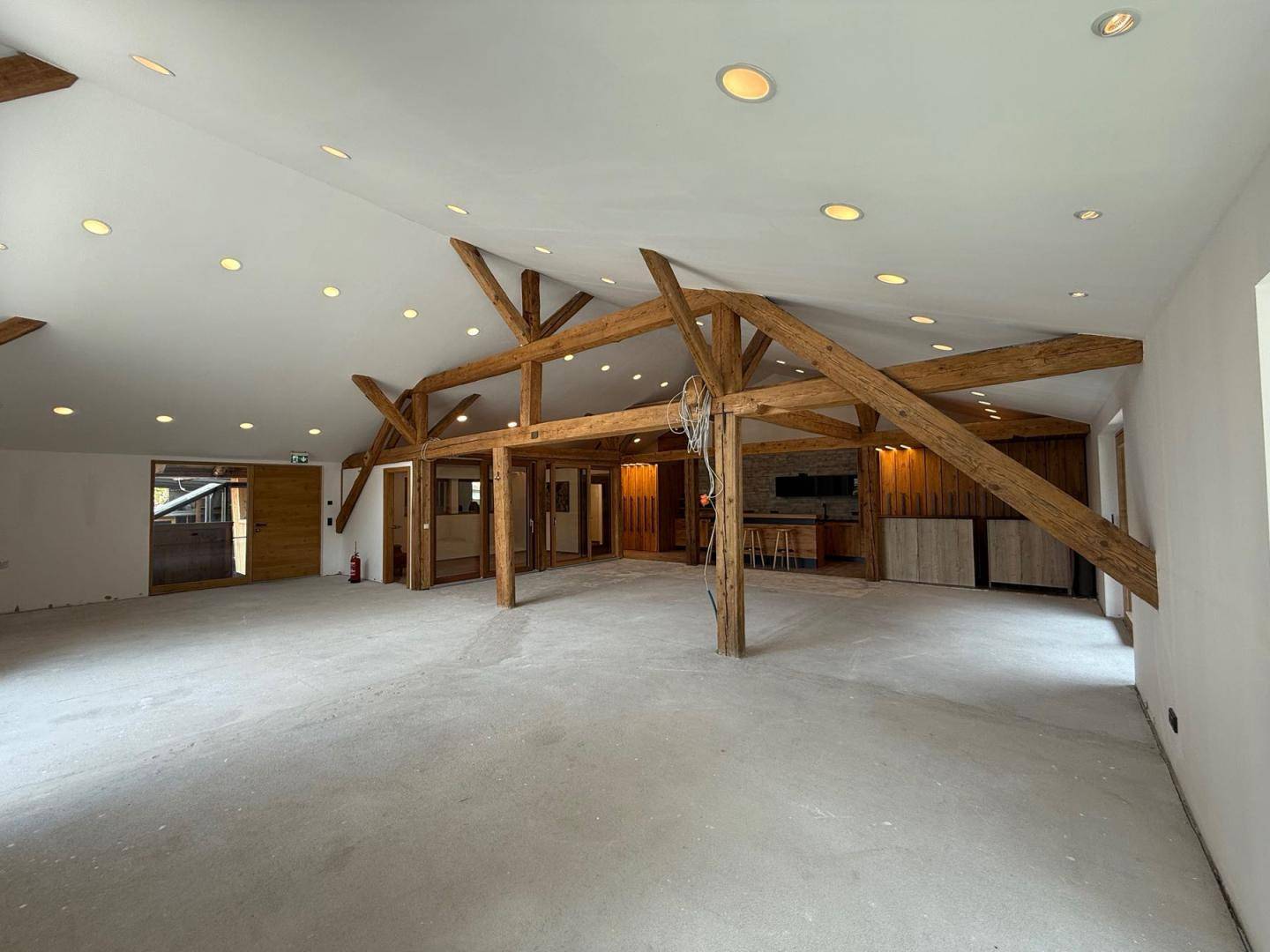 Geräumiger, offener Bereich mit Holzbalken und Betonboden, ideal für vielseitige Nutzung.